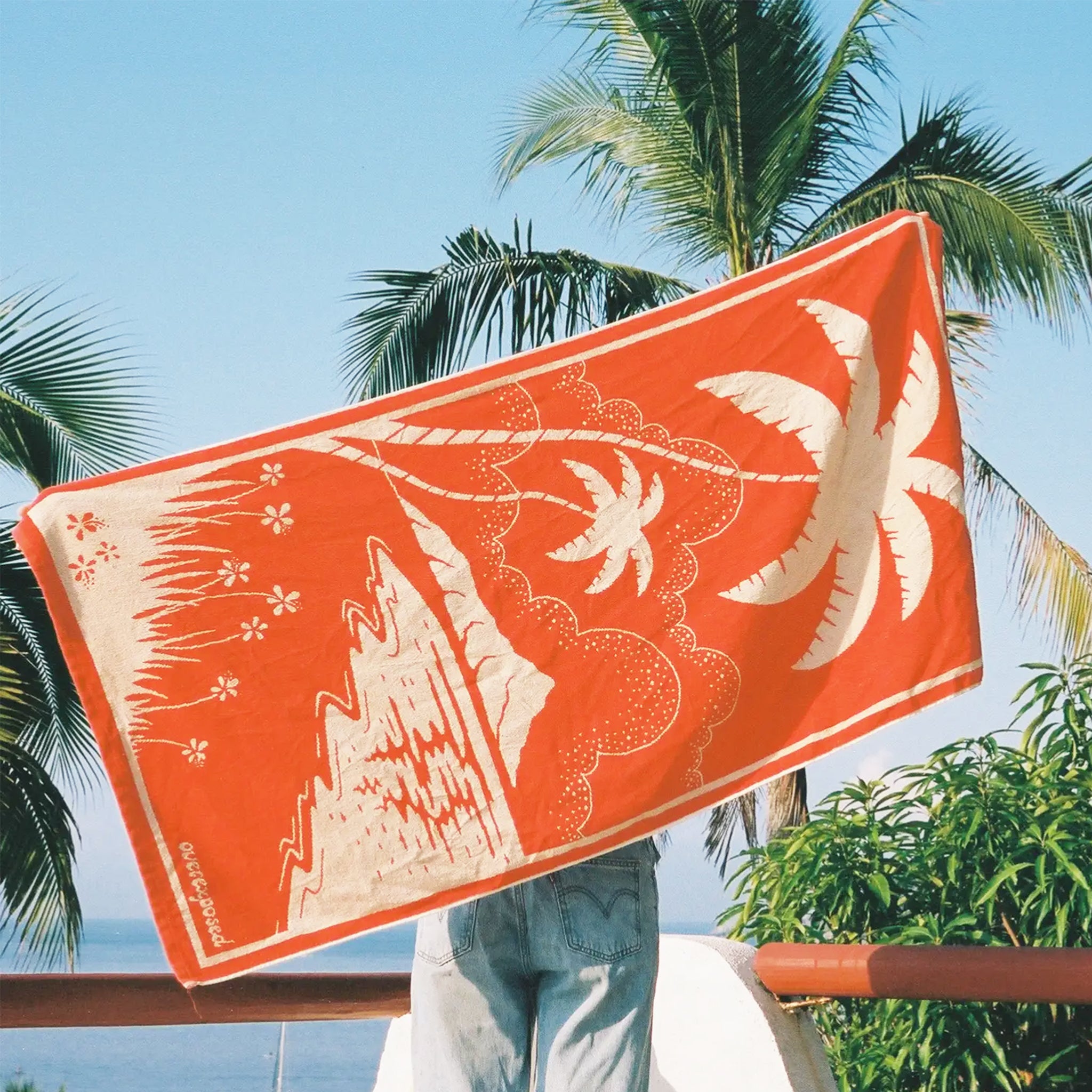 A beach towel with a palm tree design.