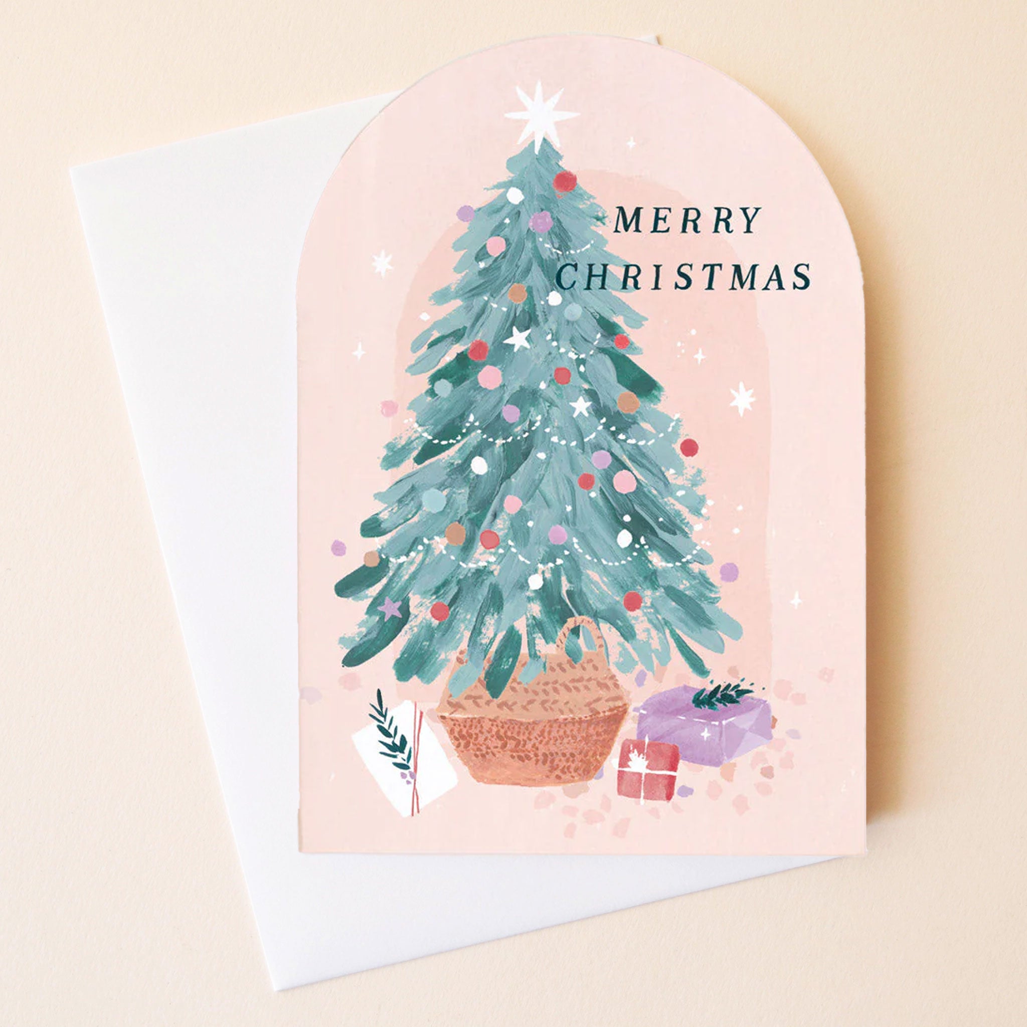 On a tan background is a pink arched card with a Christmas tree and black text that reads, "Merry Christmas". 