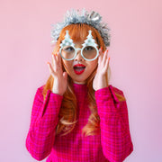 A pair of mint holiday glasses with tree shapes and six white pom poms and a star on top.