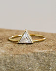 A gold ring with a triangle CZ stone in the center. 