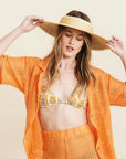 A woven bucket hat in a light straw color with a frayed edge detail along the edge of the brim and a tiny hemlock hat metal emblem in the center.