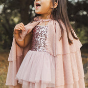 A dusty pink tulle cape with tiered layers and a tie at the neck. 