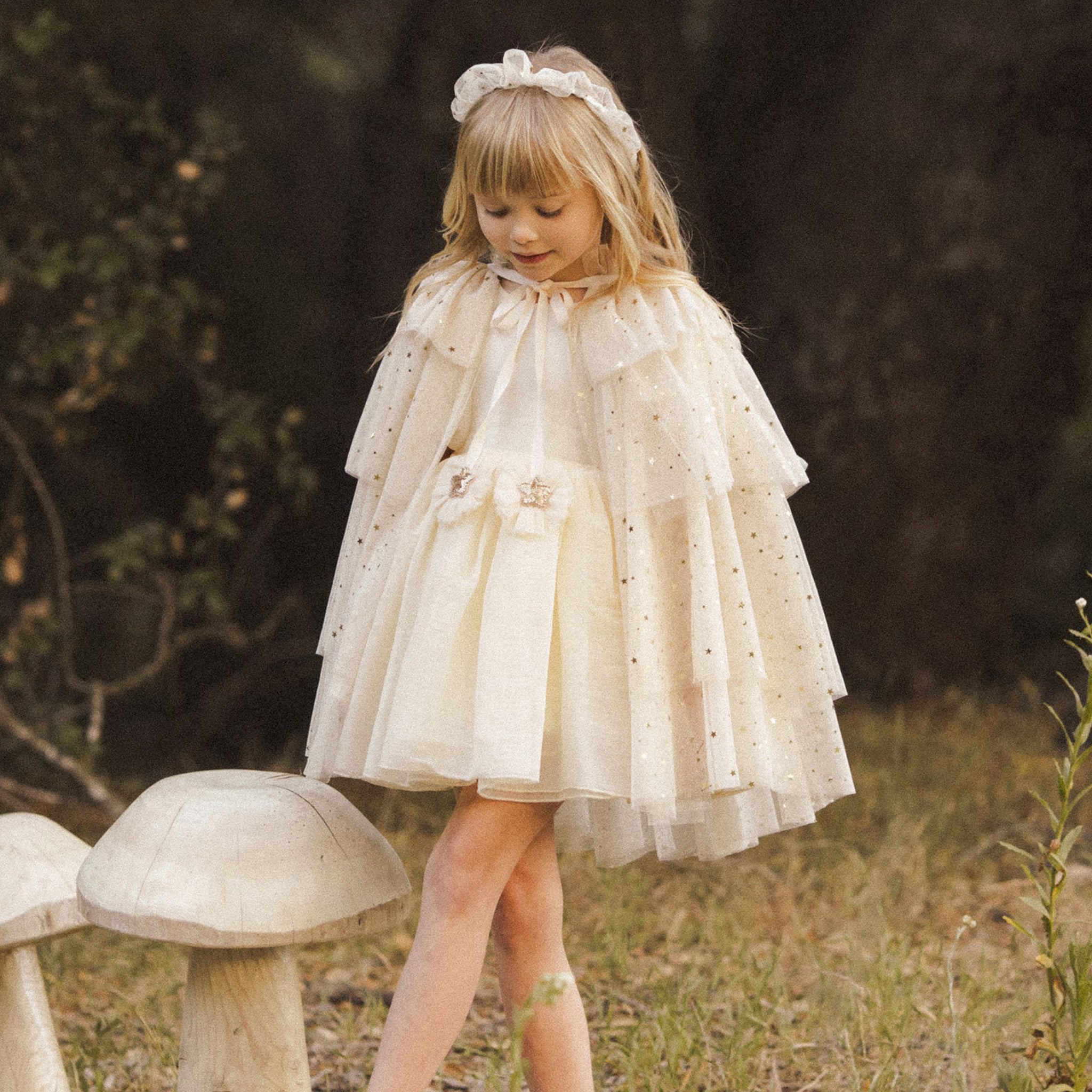 A champagne colored tulle cape with layered tiers and a neck tie with two star ribbons.