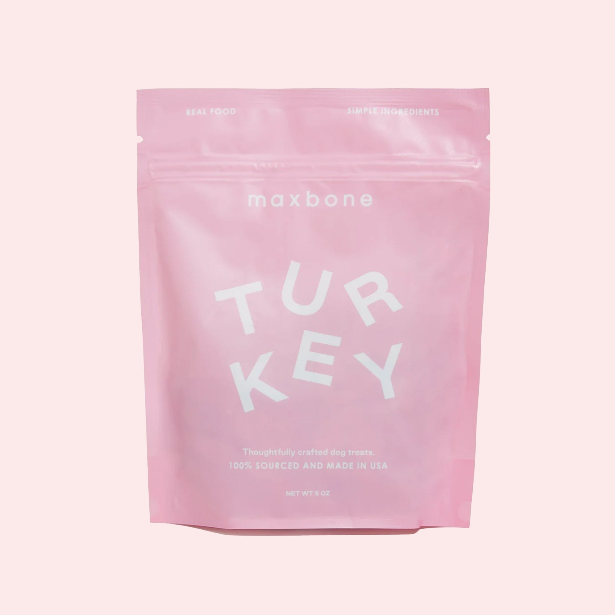 A light pink resealable bag filled with turkey flavored dog biscuits. The packaging reads, "Maxbone | Turkey | Thoughtfully crafted dog treats 100% sourced and made in USA" in white text.