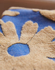 A blue hand towel with a cream floral print design and fringe details on each end. 