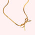 A gold herringbone chain necklace tied in a bow. 