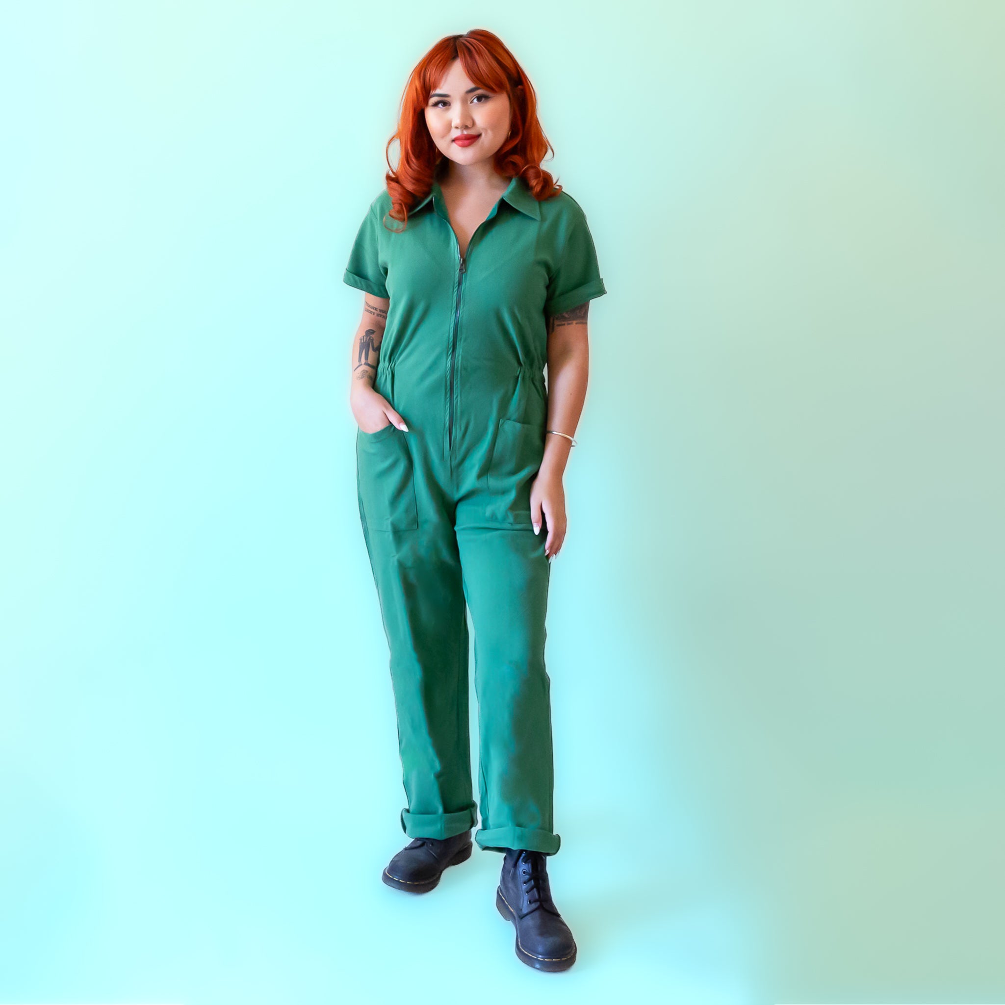 A green short sleeve jumpsuit with a zipper up the front. 