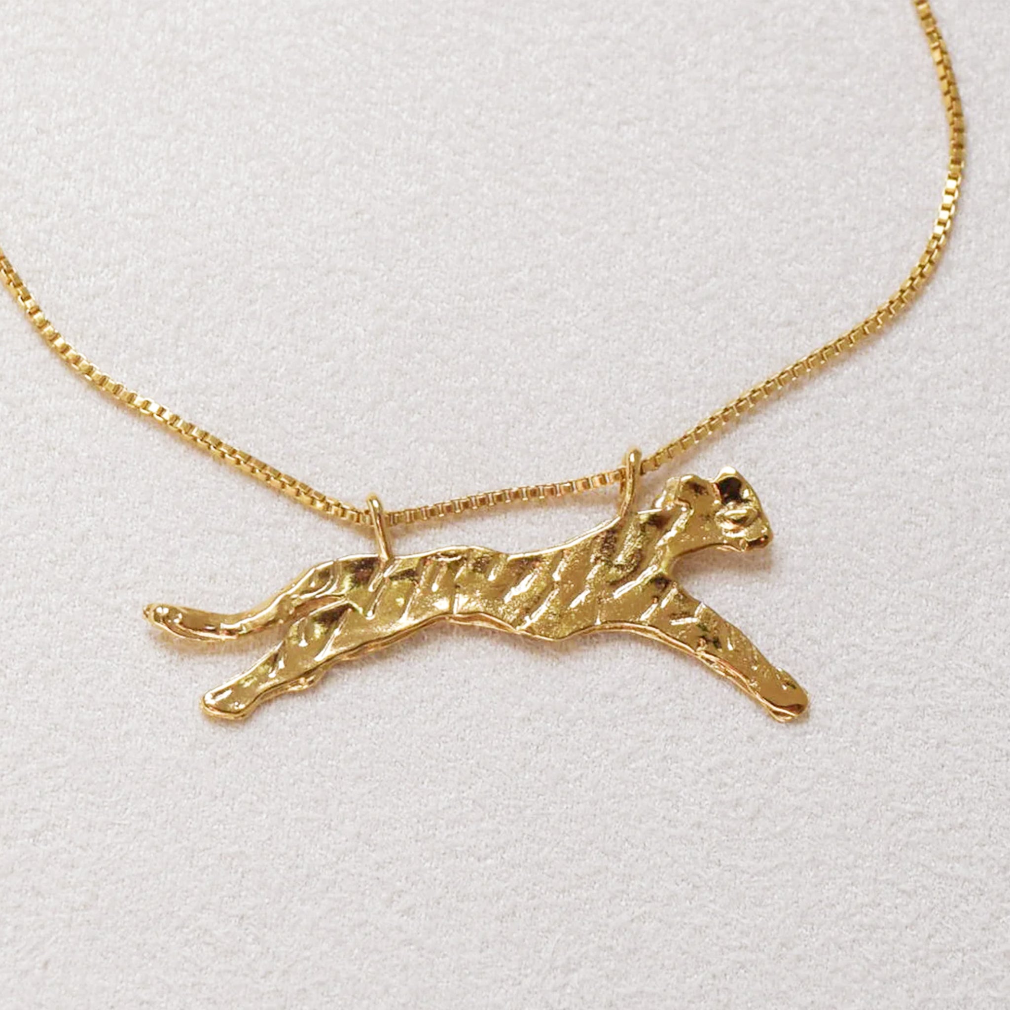 A leopard shaped gold pendant with a gold chain necklace.