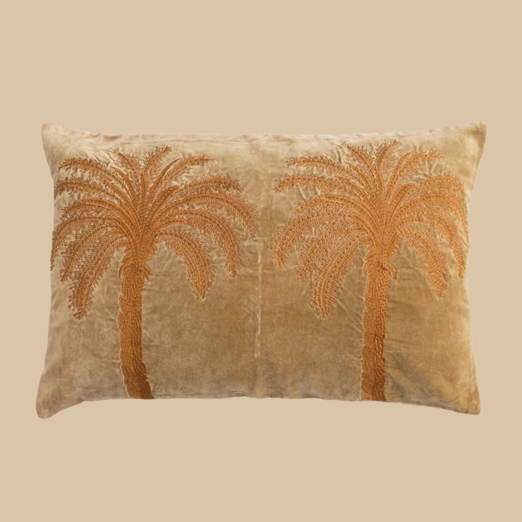 A burnt orange velvet pillow with embroidered orange palm trees, a removable cover that features a zip detail. 