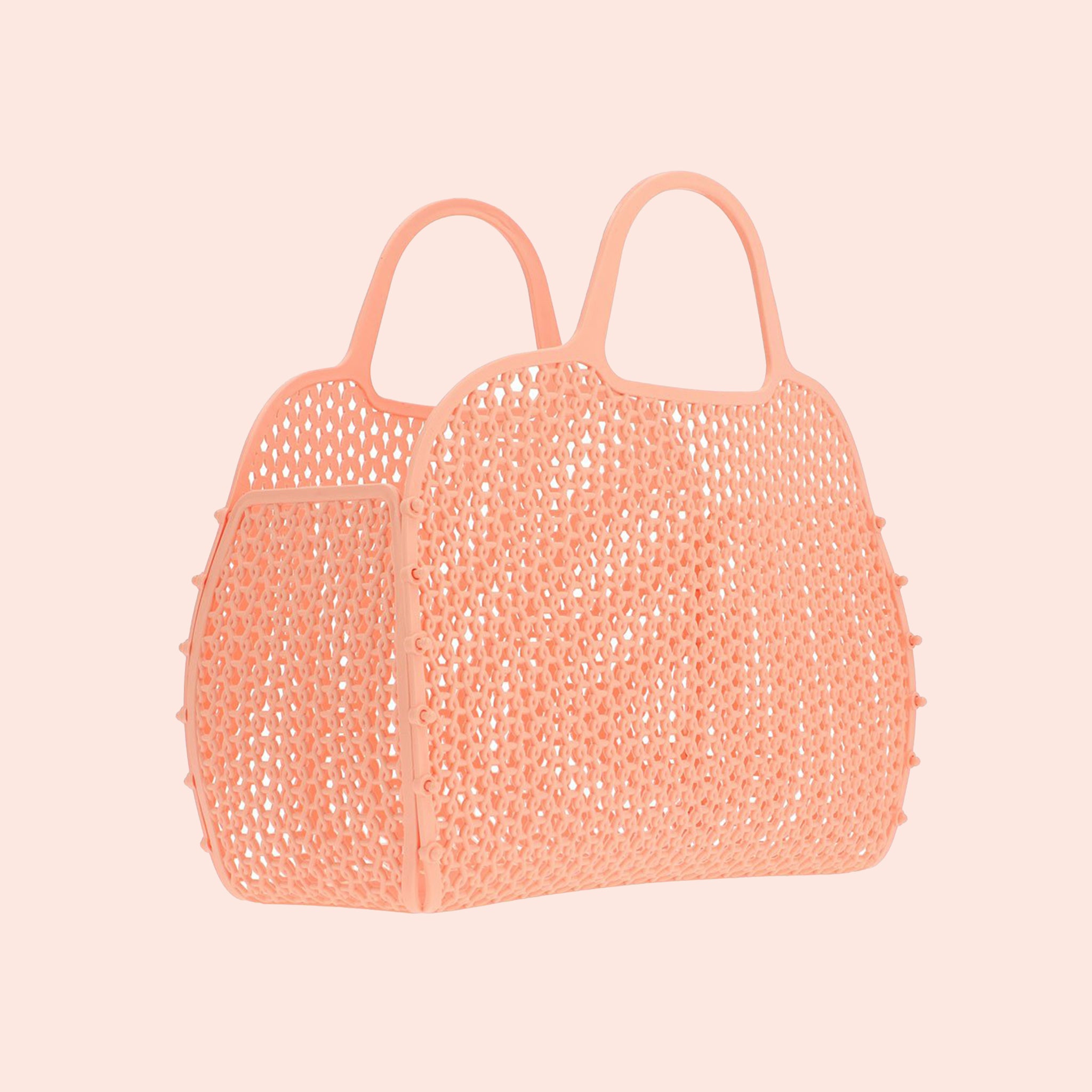 An apricot colored woven plastic handbag with two handles.