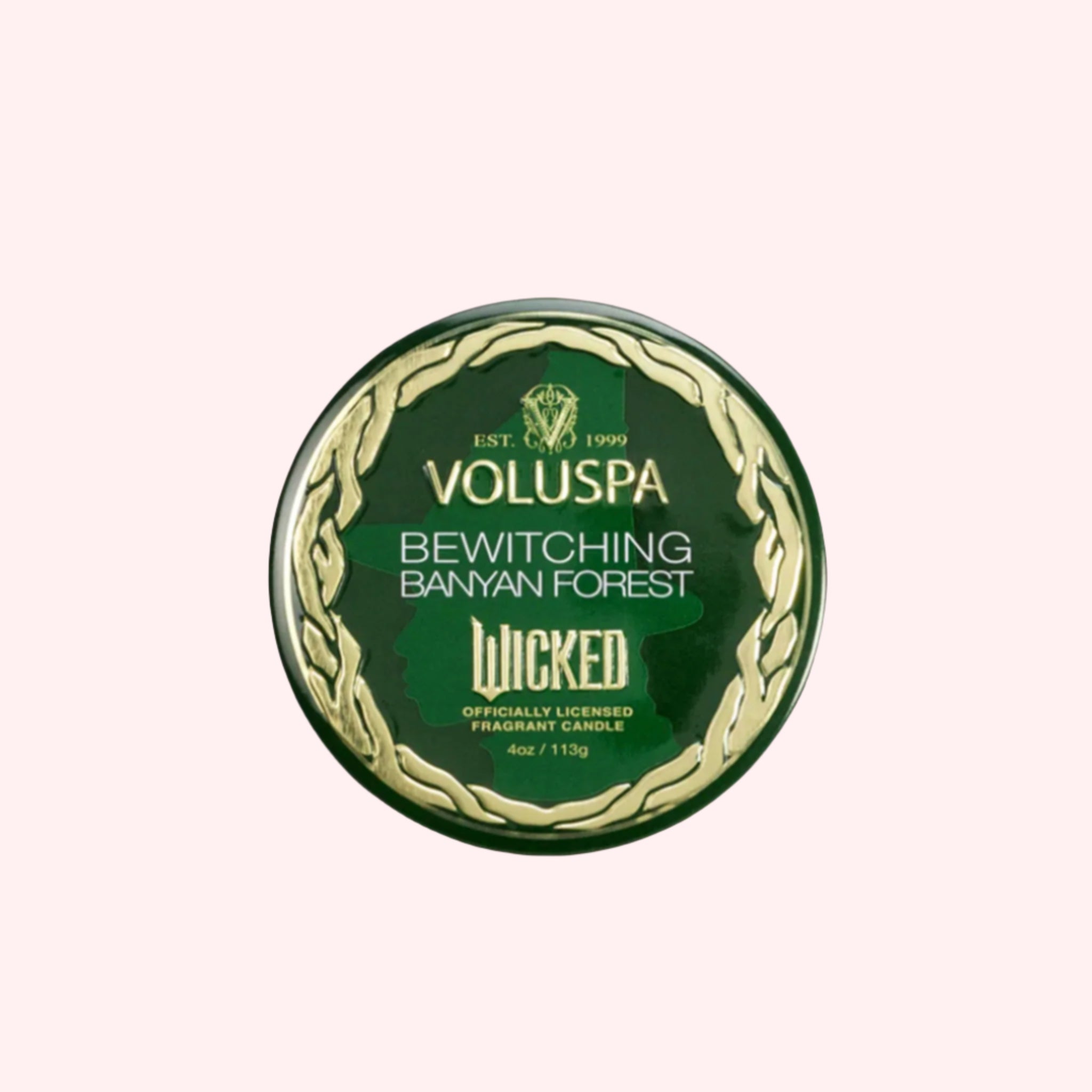 A green tin candle with gold details that reads, 'Voluspa, Bewitching Banyan Forest' Wicked. 