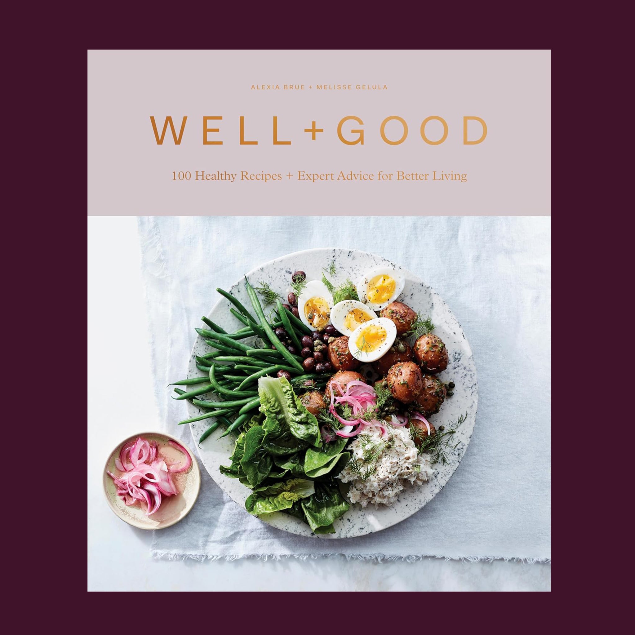 Hard cover cookbook titled 'Well + Good, 100 healthy recipes + expert advice for better living' in gold lettering. Below the title is a beautifully plated salad of greens, eggs, rice and more.