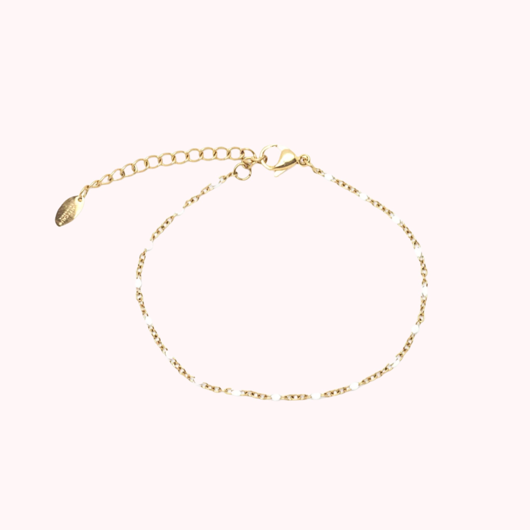 A gold bracelet with white enamel accents in between the chains.