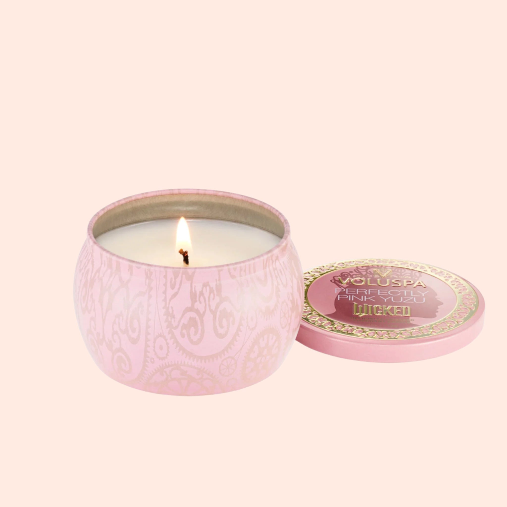 A small tin candle with a pink and gold detailed design that reads, &#39;Voluspa Perfectly Pink Yuzu Wicked&#39;. 