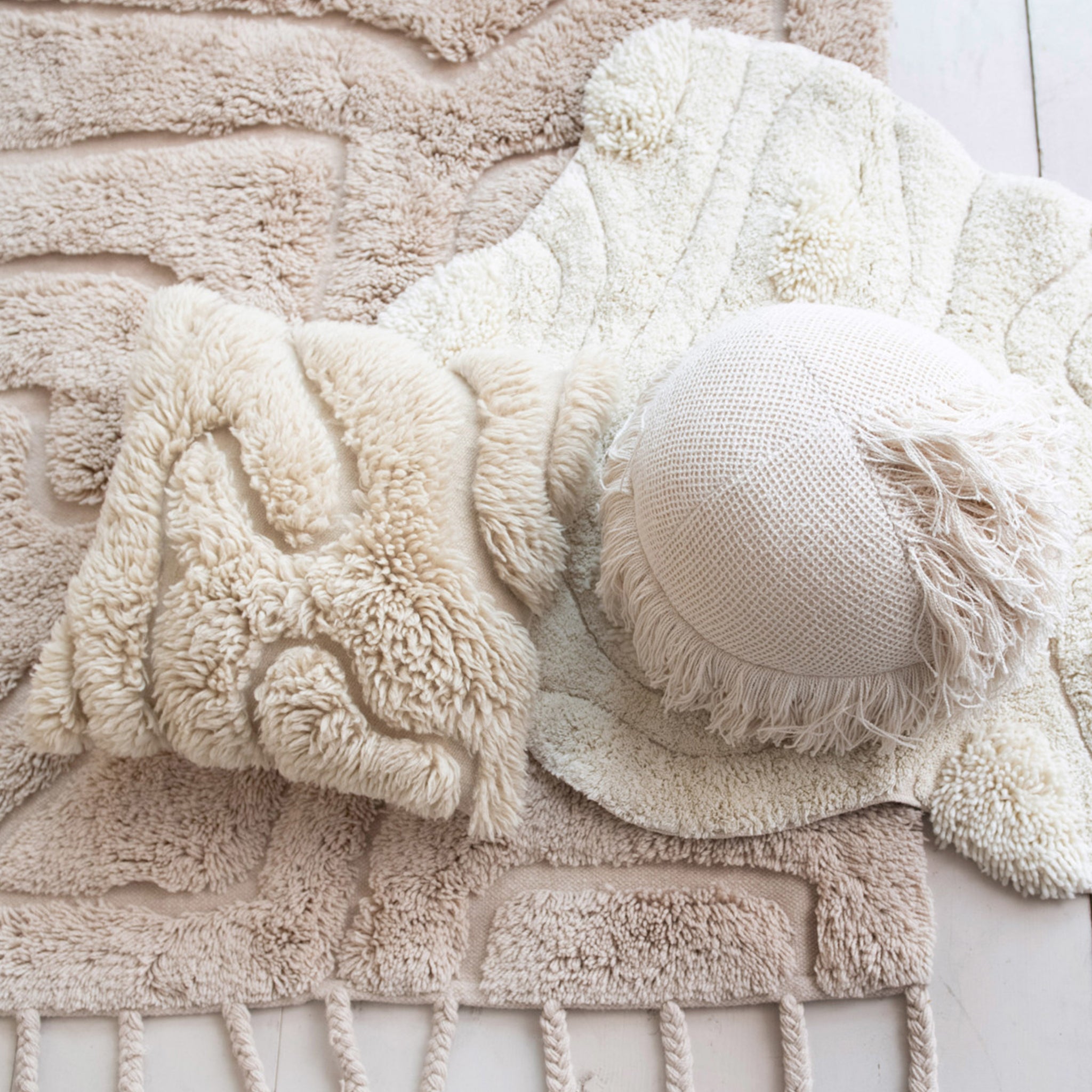 A square, cream colored cotton shag pillow with a wavy design within the shag. 