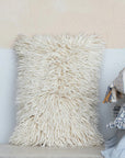An ivory wool shag lumbar pillow. 