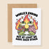 A white card with a graphic of two frogs holding hands with fire in the background and text above and below that reads, "World's Ending But At Least We Have Each Other". 