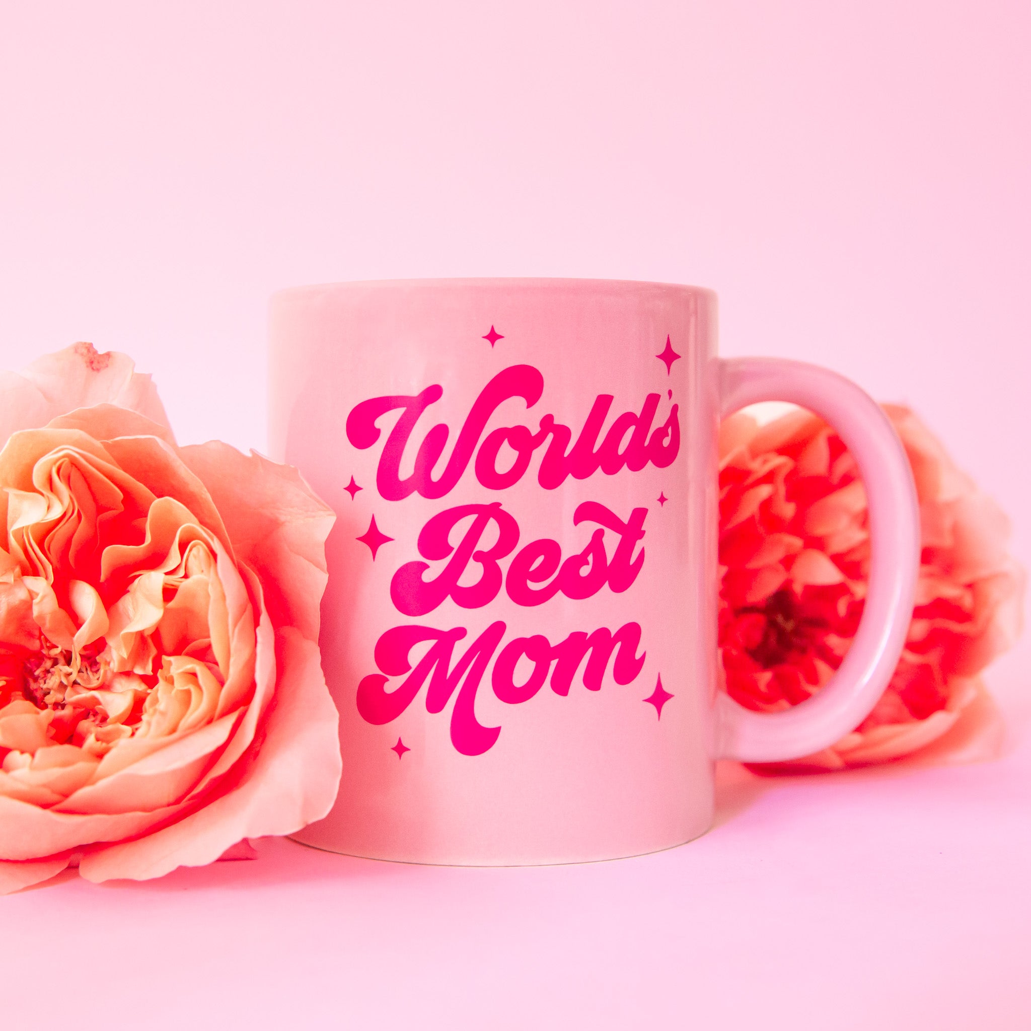 A pink mug with hot pink text that reads, 'World's Best Mom'. 