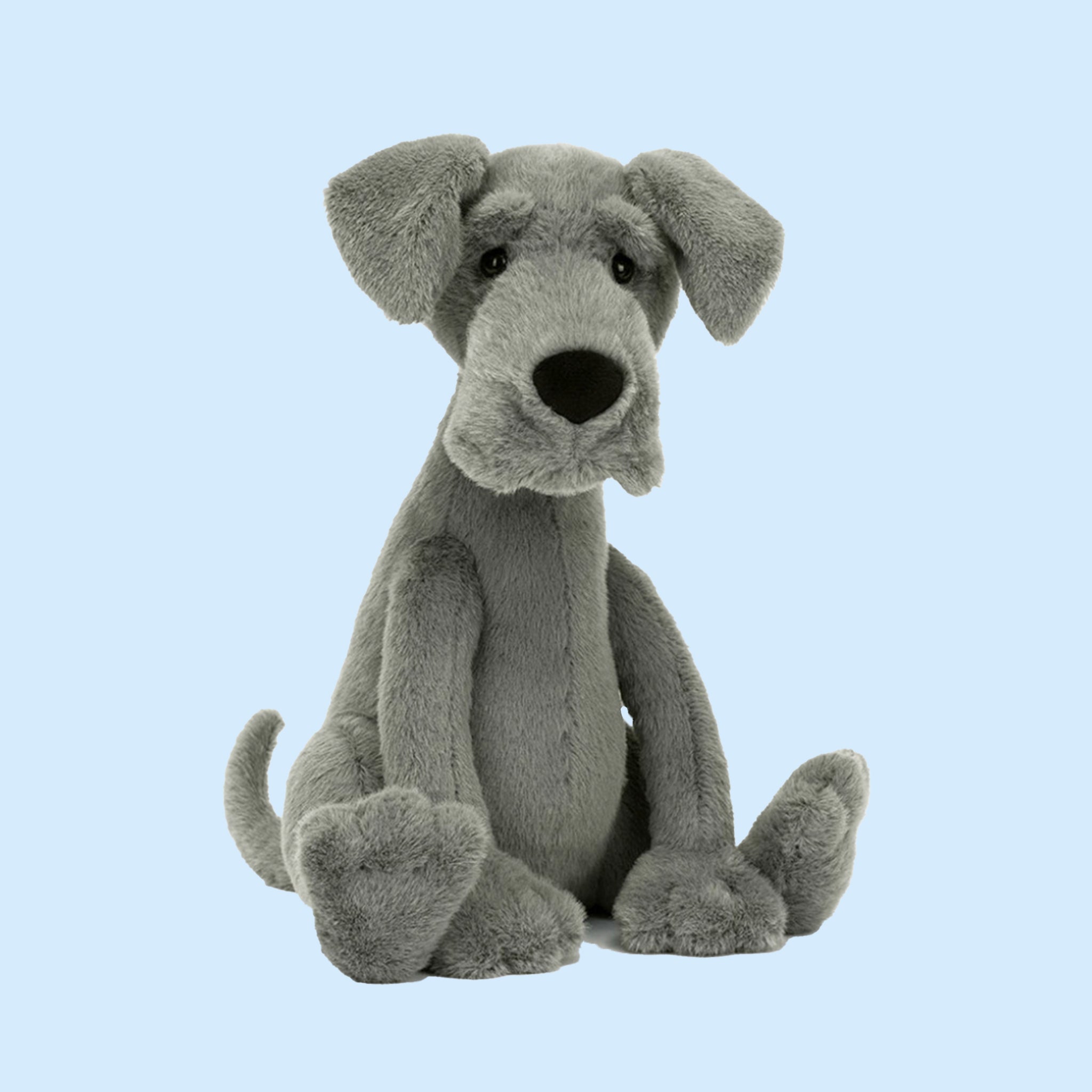 On a blue background is a greyish blue great dane shaped stuffed animal. 