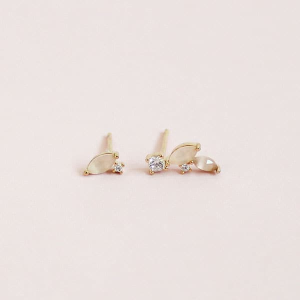 On a cream background is a pair of mismatched earrings with a straight pack post and CZ studs.