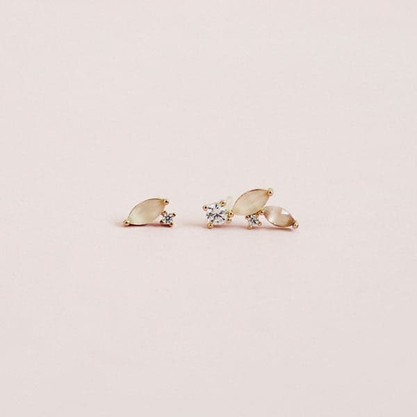 On a cream background is a pair of mismatched earrings with a straight pack post and CZ studs. 