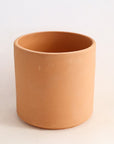 On a white background is a terracotta cylinder planter with a raw terracotta finish. 