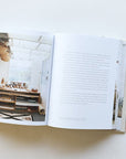 Books lays open on a table. The left page shows a picture of a indoor porch workshop, the left page is filled with text.