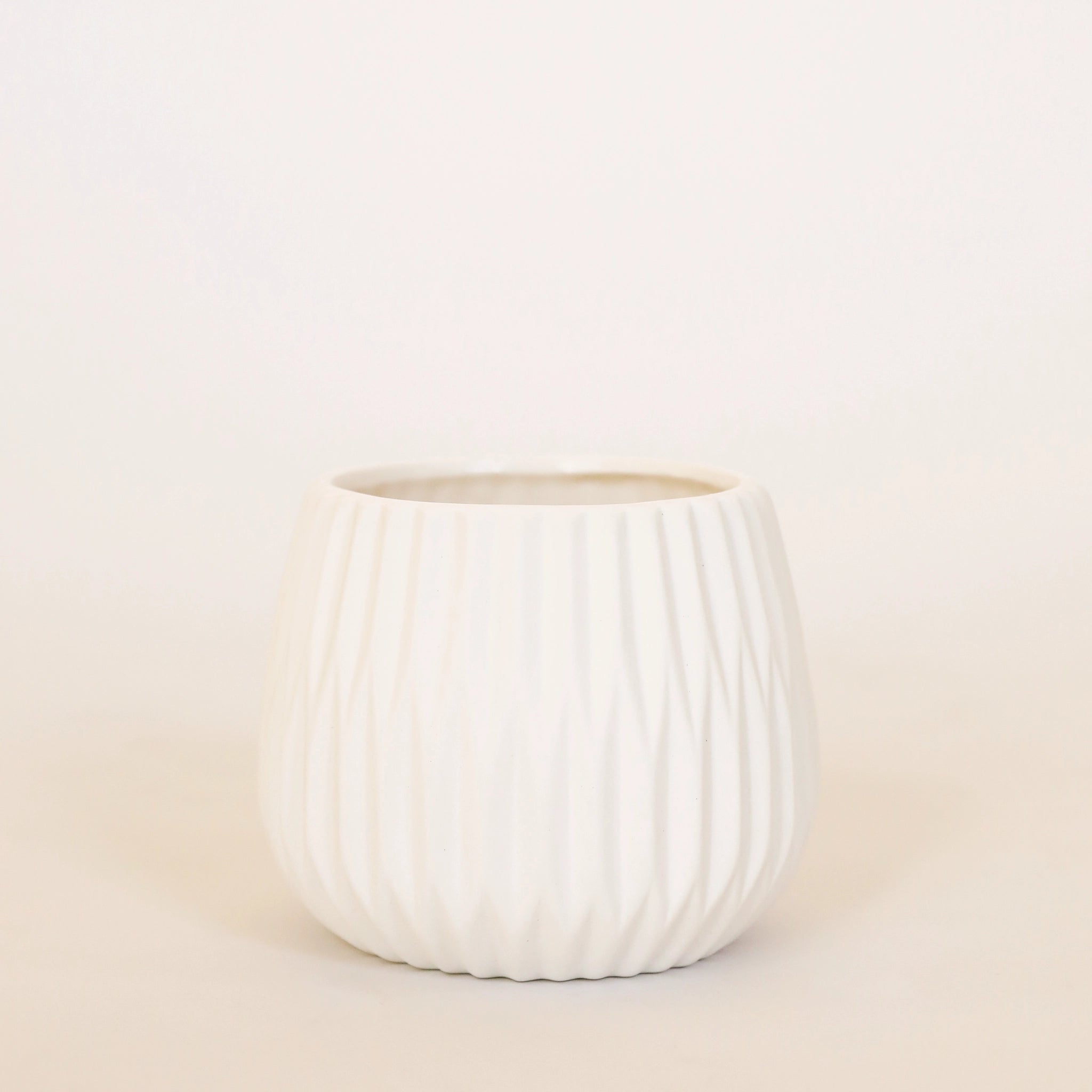 A matte white ceramic planter with fluted detailing.