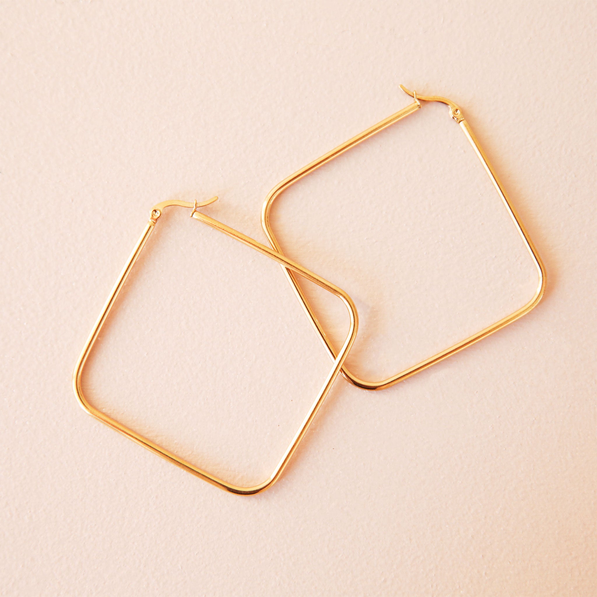 Thin square hoop earrings that hang in a diamond shape. 