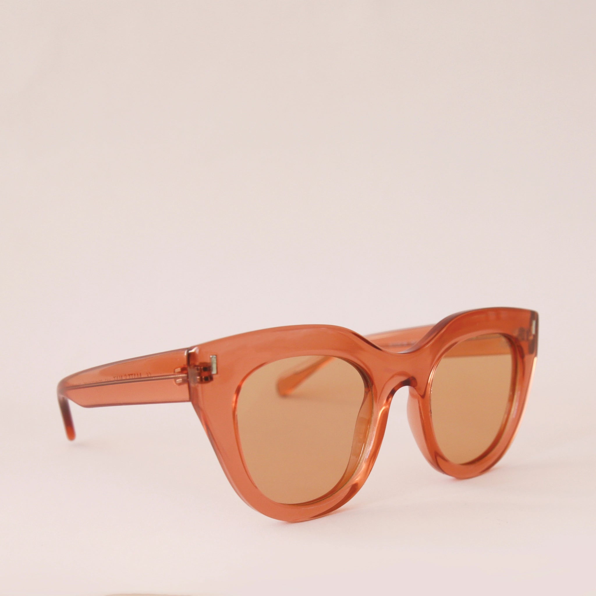 Orange sunglasses with a rounded edge and a slight cat eye shape along with orange lenses.