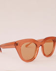 Orange sunglasses with a rounded edge and a slight cat eye shape along with orange lenses.