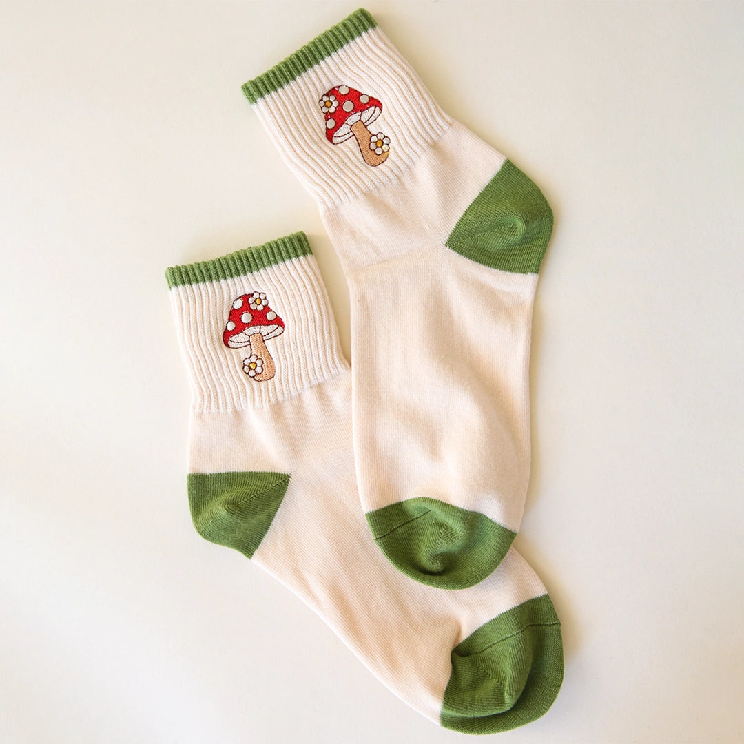 White crew socks with green accents and a red and white mushroom graphic on the ankle.