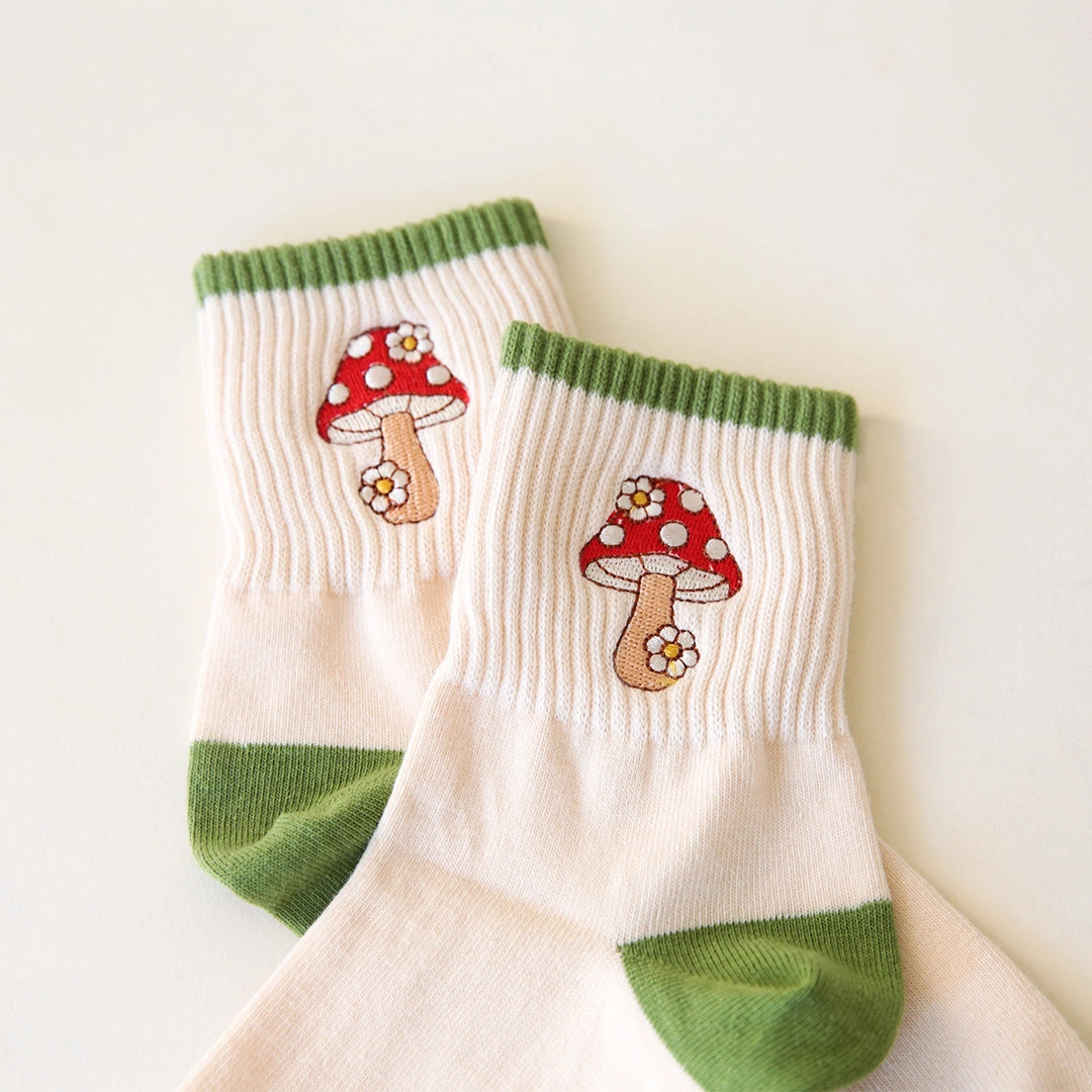 White crew socks with green accents and a red and white mushroom graphic on the ankle.