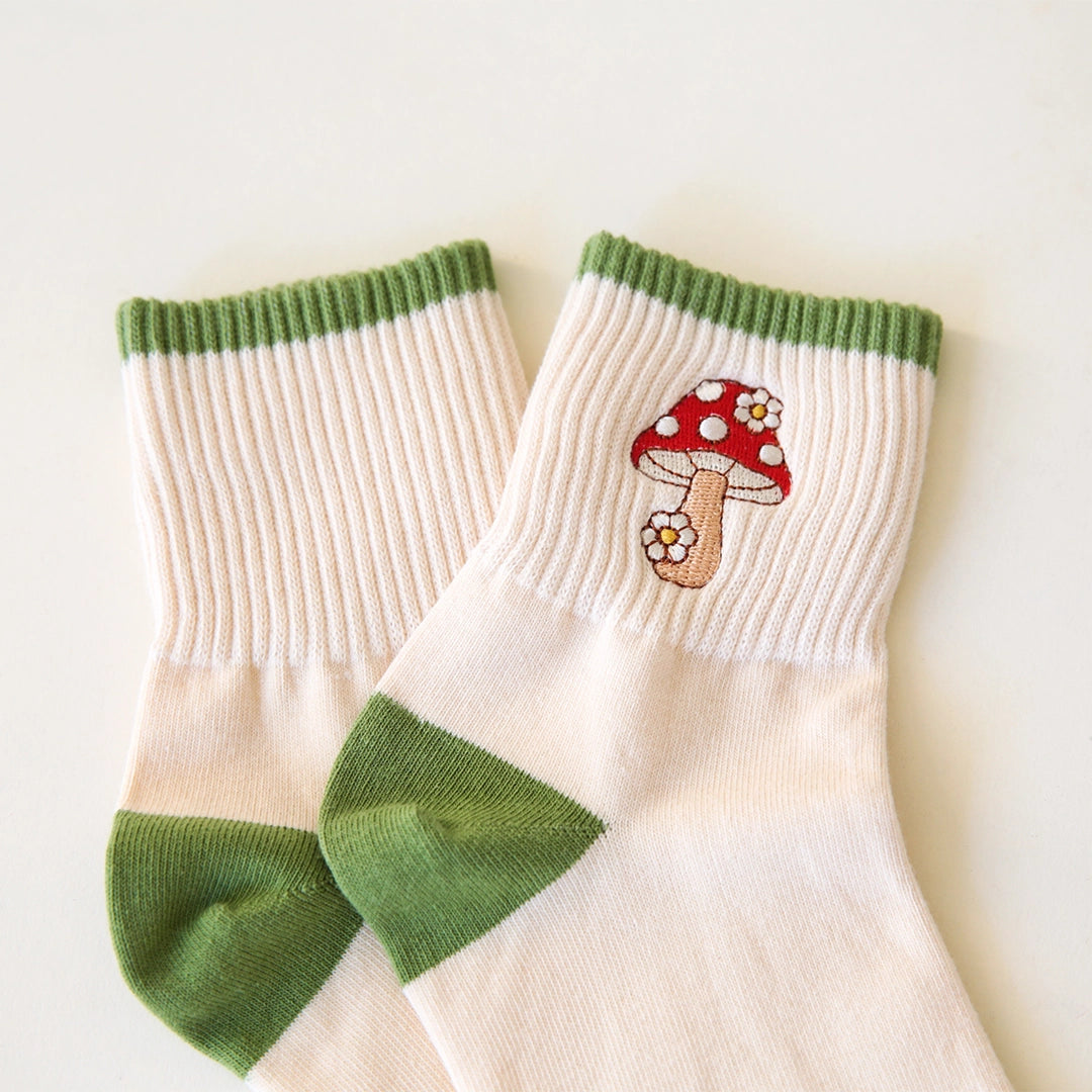 White crew socks with green accents and a red and white mushroom graphic on the ankle.