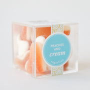 A clear acrylic box with peaches and cream candies inside. They look like small orange slices with a white bottom.