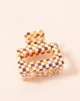 A white and brown acrylic checkered claw hair clip with a square shape and two simple geometric cutouts.