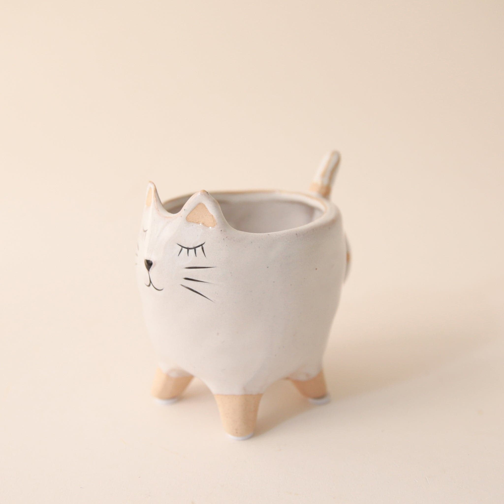 a small white planter shaped as a cat with a painted cat face and tail.