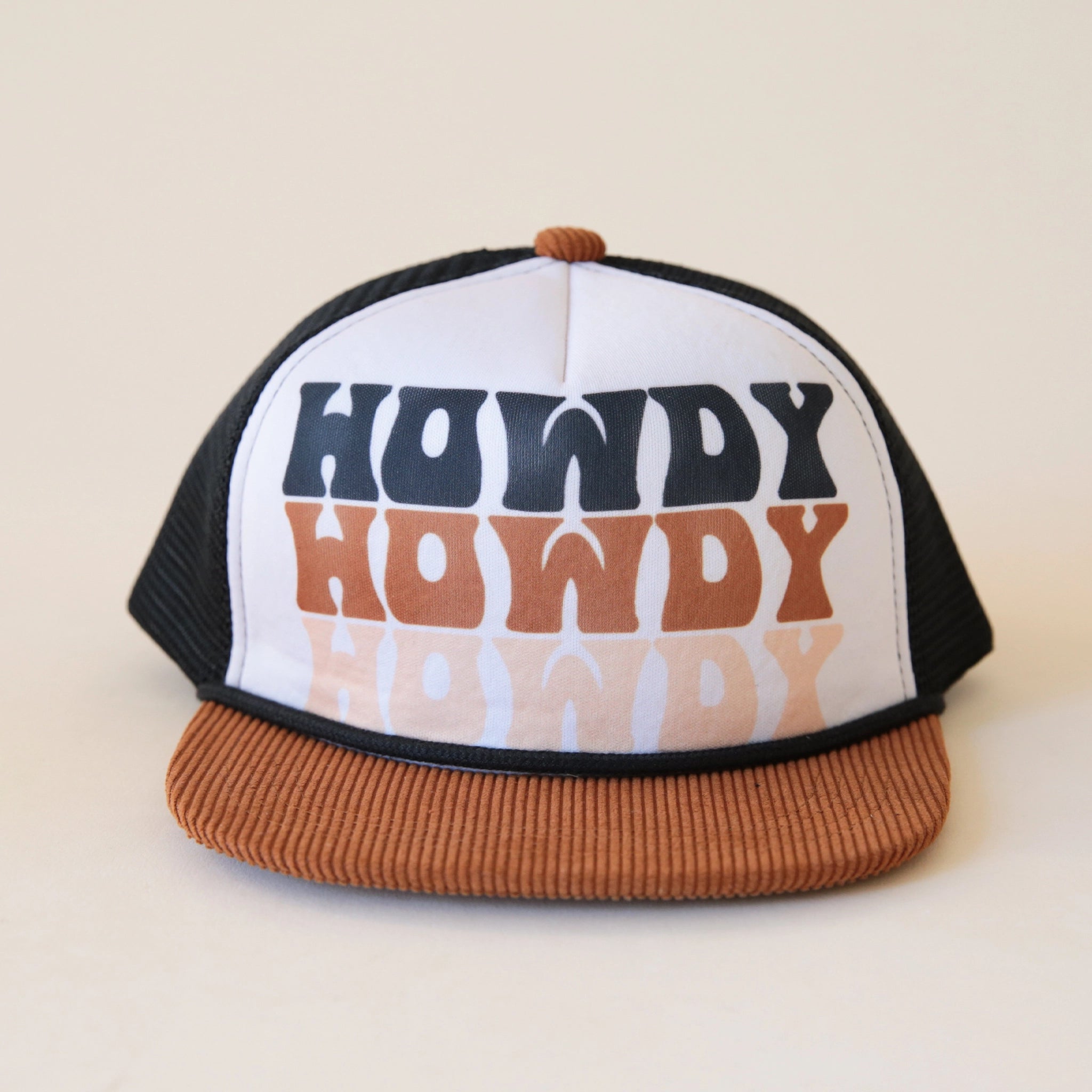 A children trucker hat with a white panel, black mesh backing and a brown corduroy bill along with text that reads, "Howdy Howdy Howdy" stacked vertically on top of one another in a black, brown, and cream colored letters.