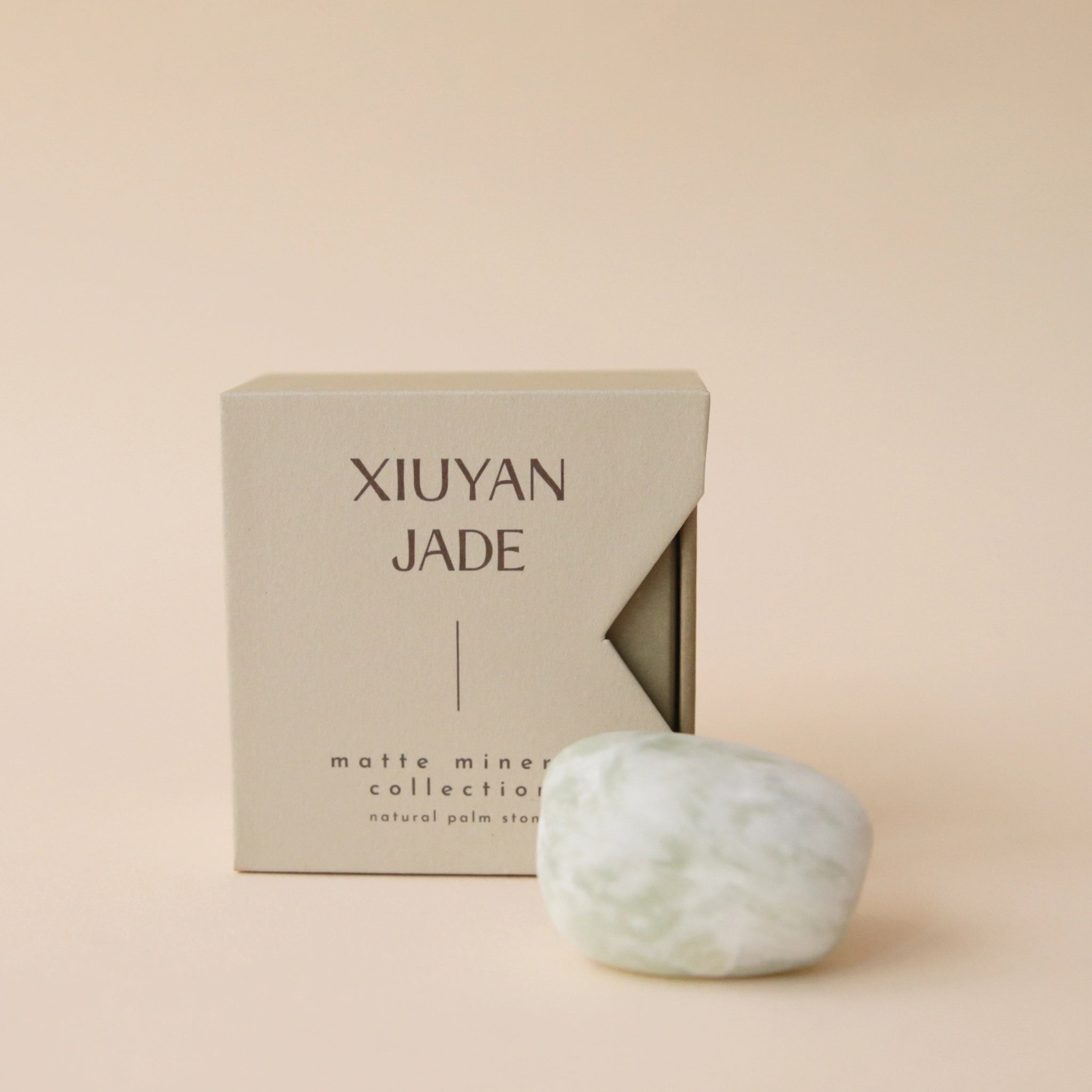 A neutral tan box that says, "Xiuyan Jade Matte Mineral Collection" in dark brown letters along with a white and light green Xiuyan Jade stone.