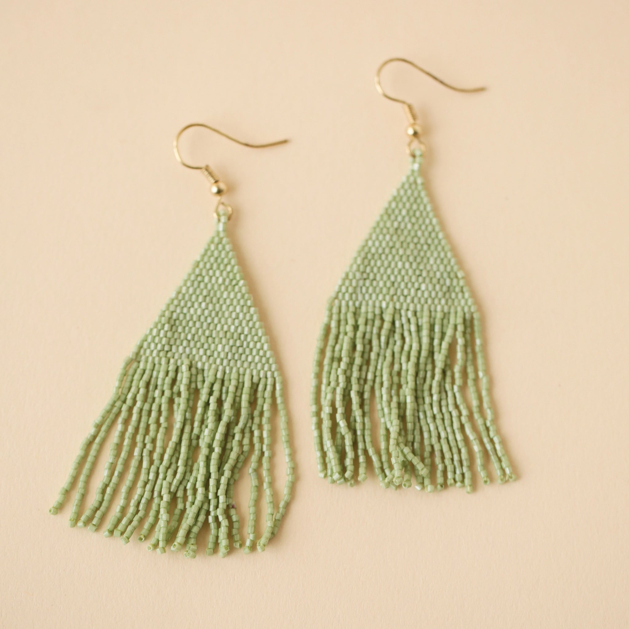 Gold plated hook earrings attached to a triangle shaped mint green beaded earrings that has a fringe detail on the bottom edge.