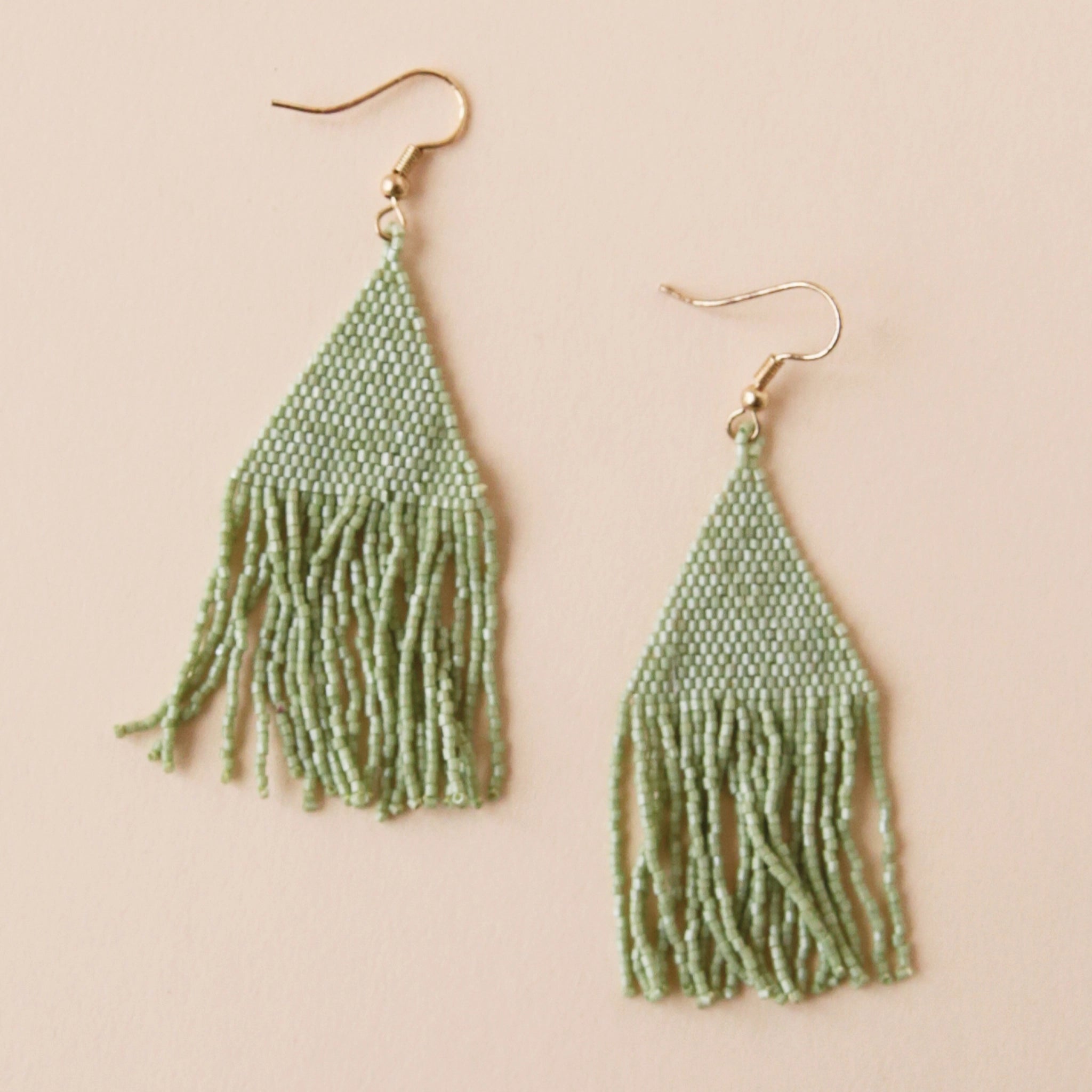 Gold plated hook earrings attached to a triangle shaped mint green beaded earrings that has a fringe detail on the bottom edge.