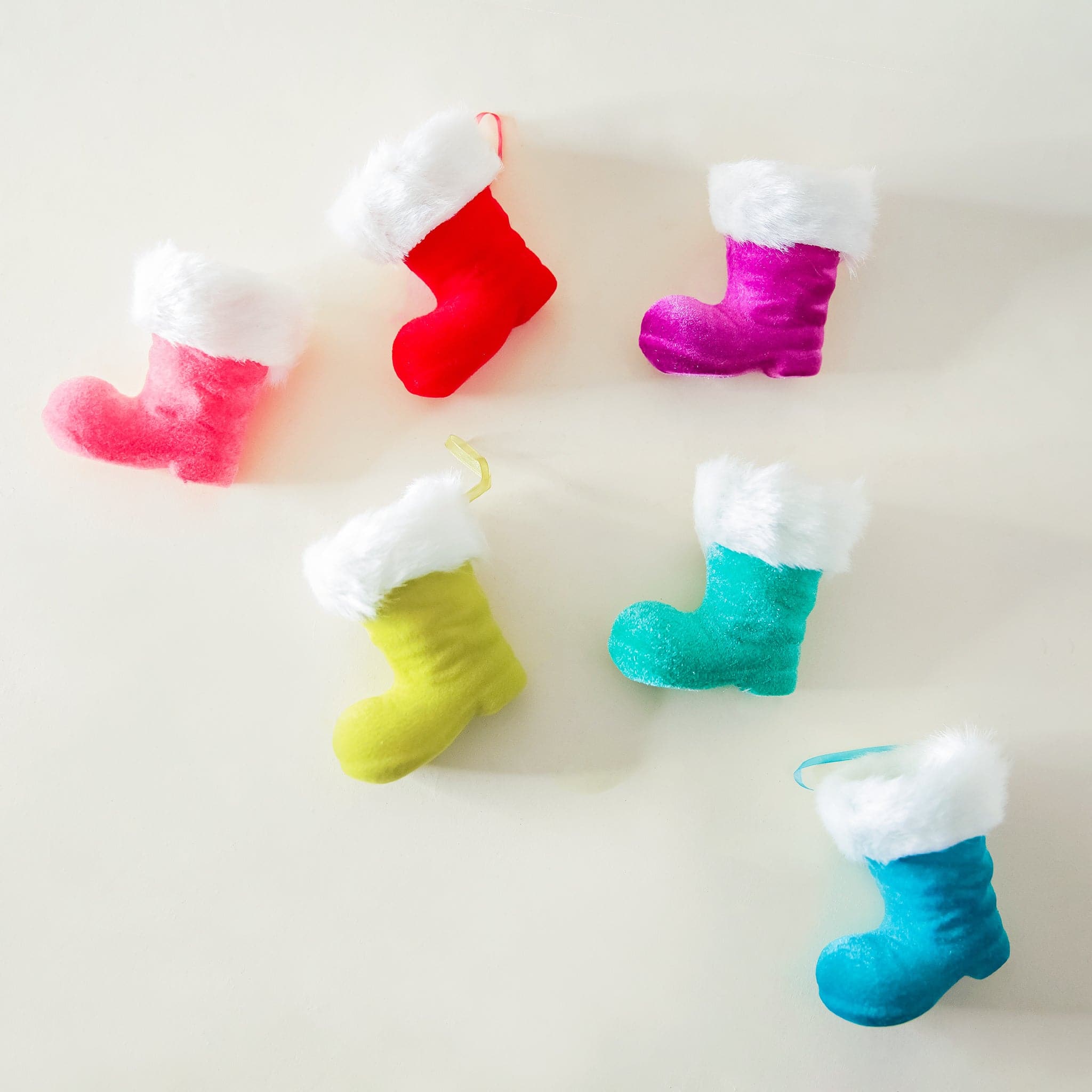 Six Santa boots each a different color with a velvety finish, a white faux fur trim and a loop on the corner for hanging.