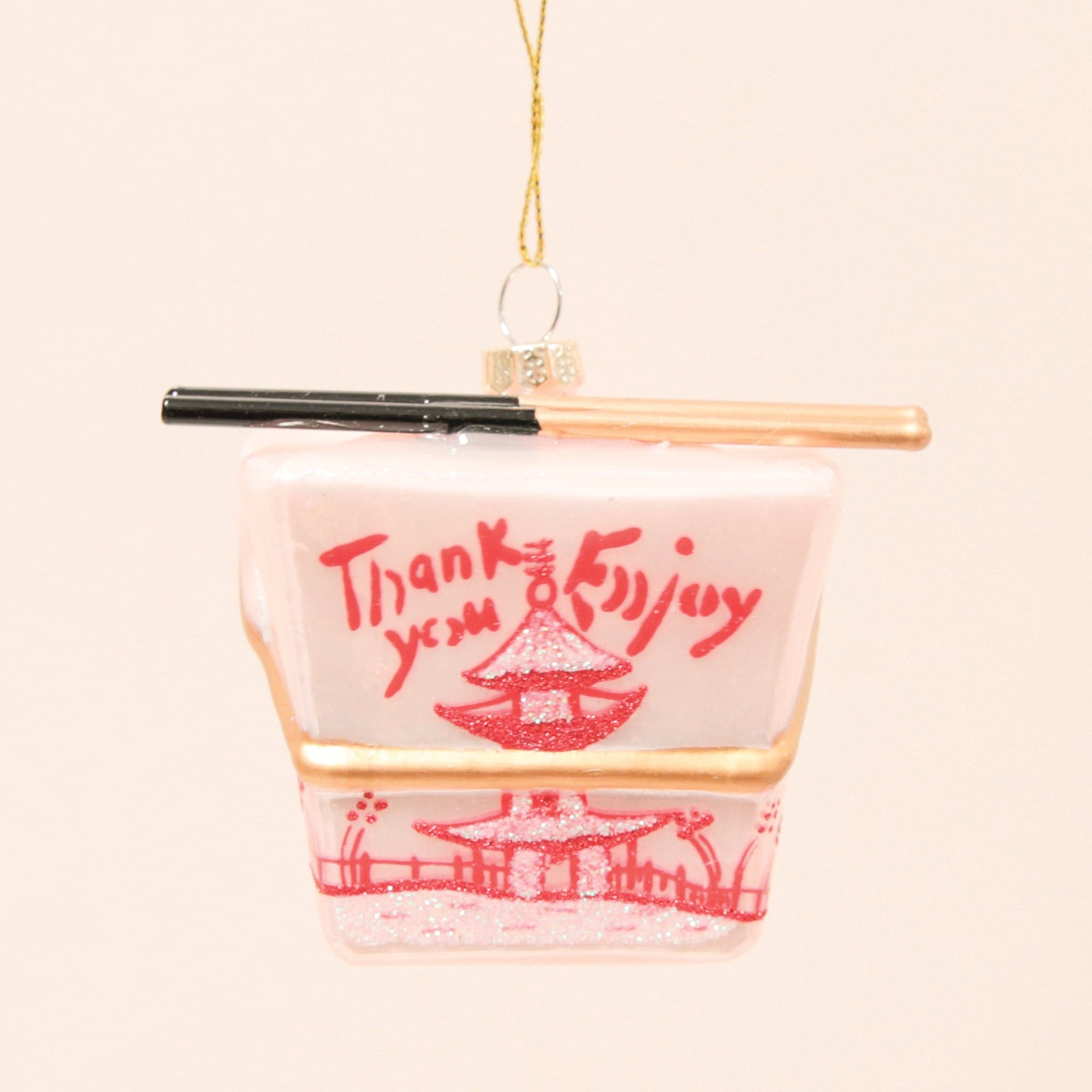 A glass ornament made to look like a pink Chinese takeout box with a pair of chopsticks across the top.