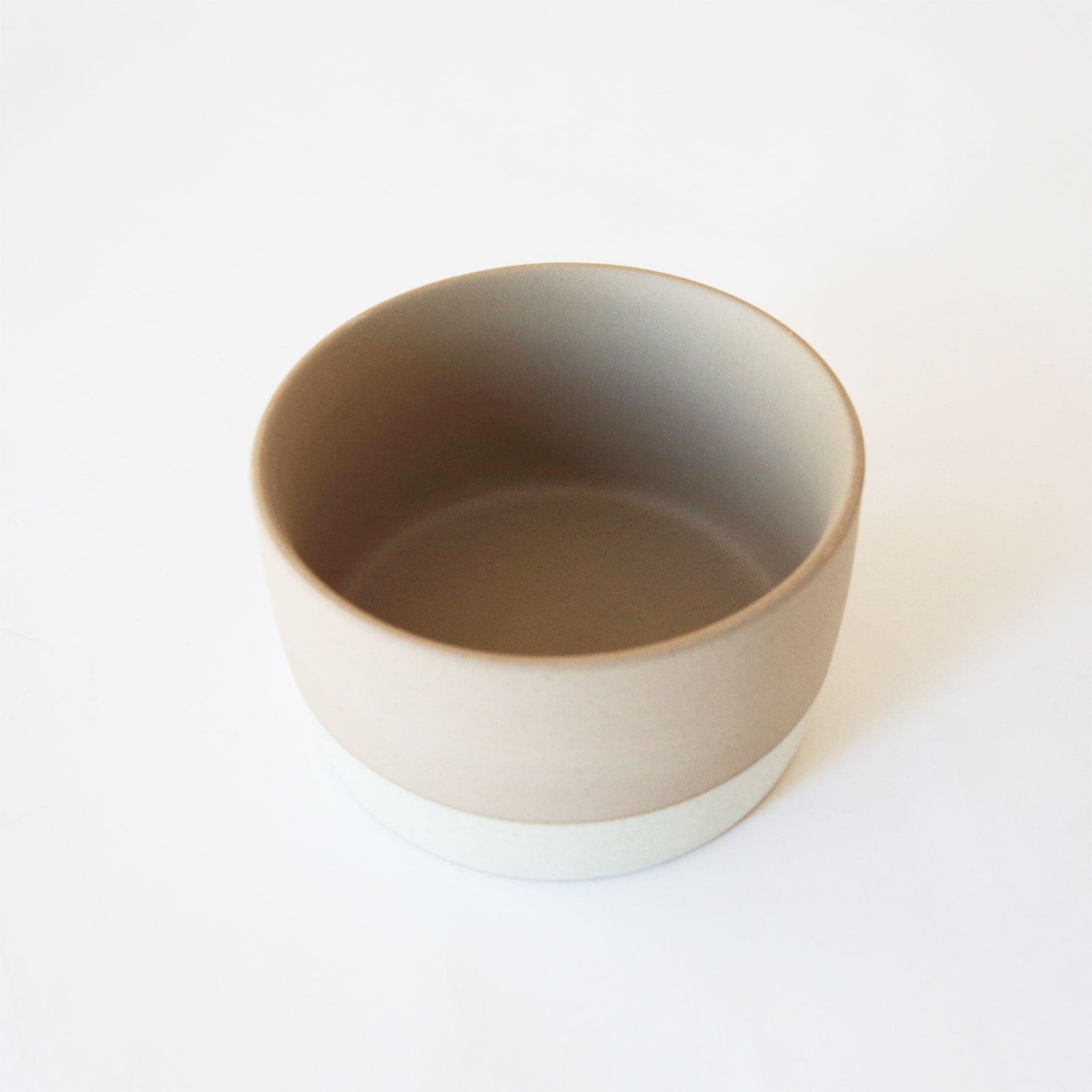 A two-toned ceramic pot with tiny black speckles. The top half is a creamy beige and the bottom is white.