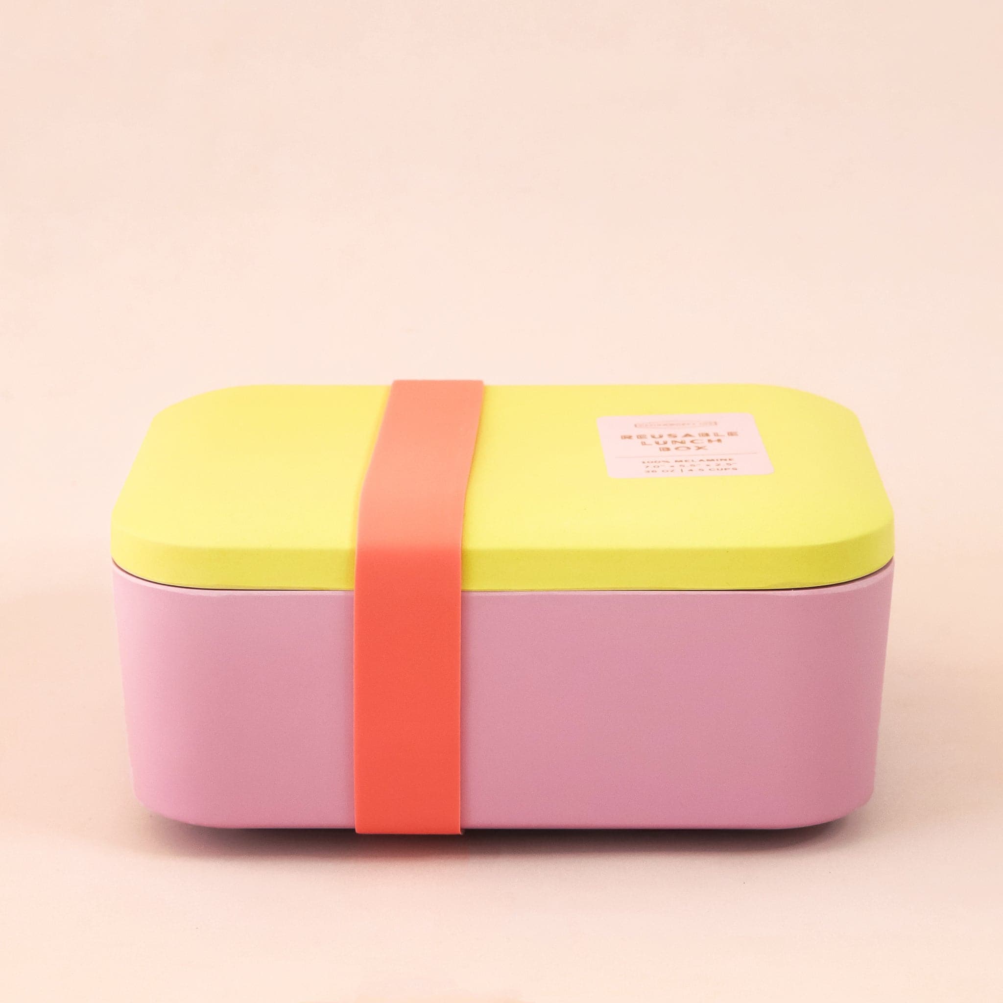 A bright pink and bright yellow lunch box with a red silicone band that goes around to keep closed. 