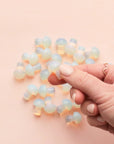 A handful of the tiny mushroom shaped Opal stones on a pink background.