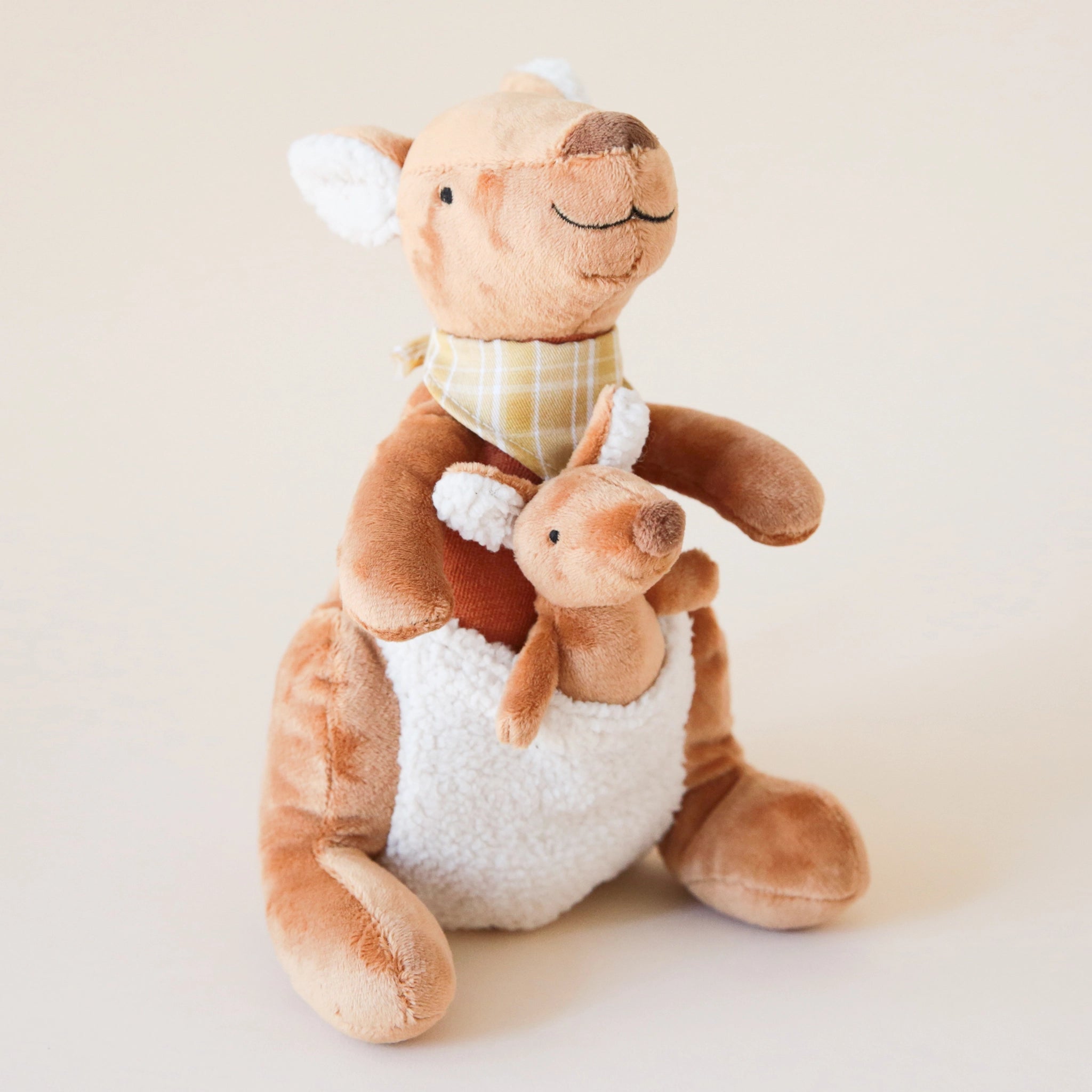 A kangaroo mama and a baby kangaroo stuffed animal with a cream pocket in the front and a tan/brown body.