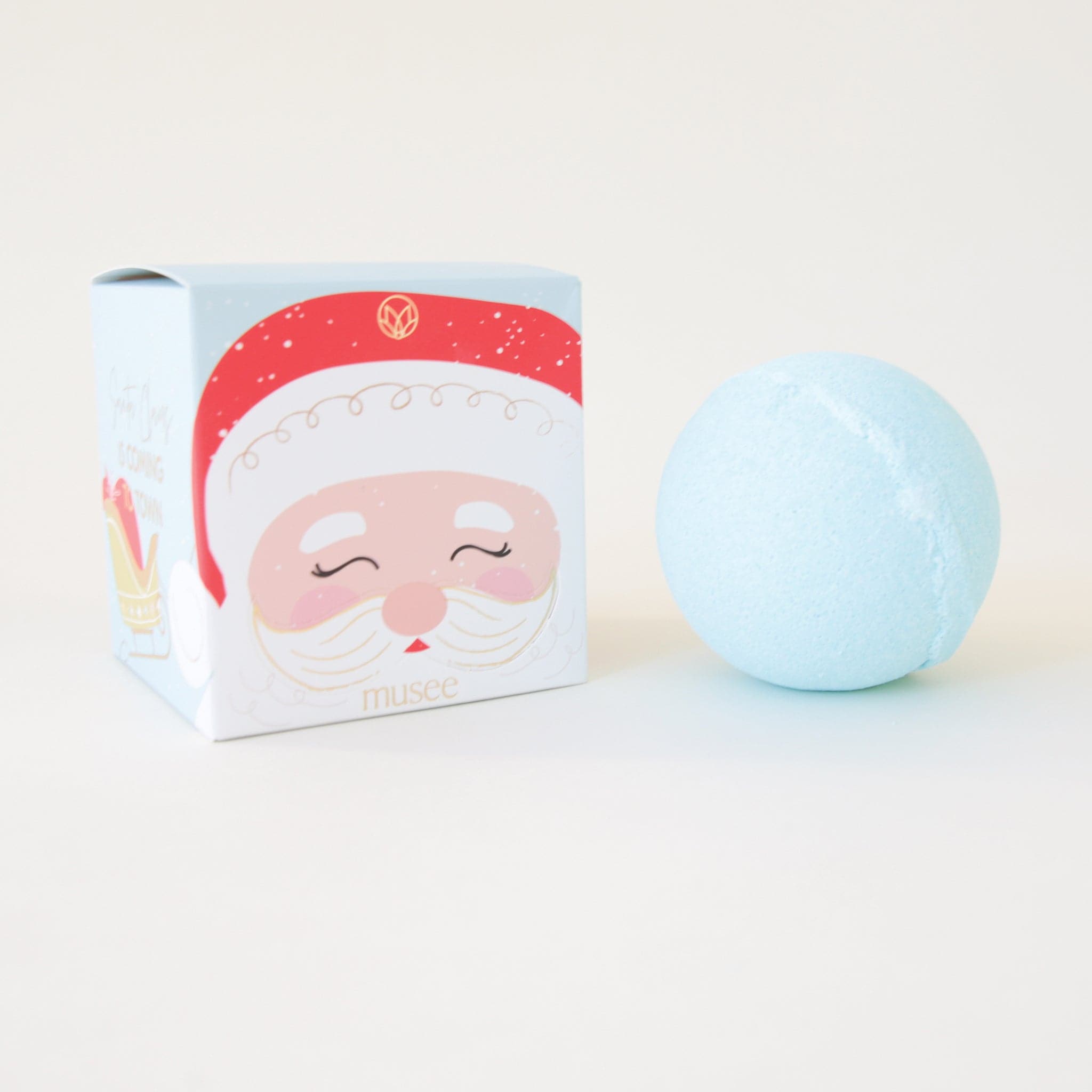 A light blue bath bomb that comes in a cardboard box with a Santa design on the front.