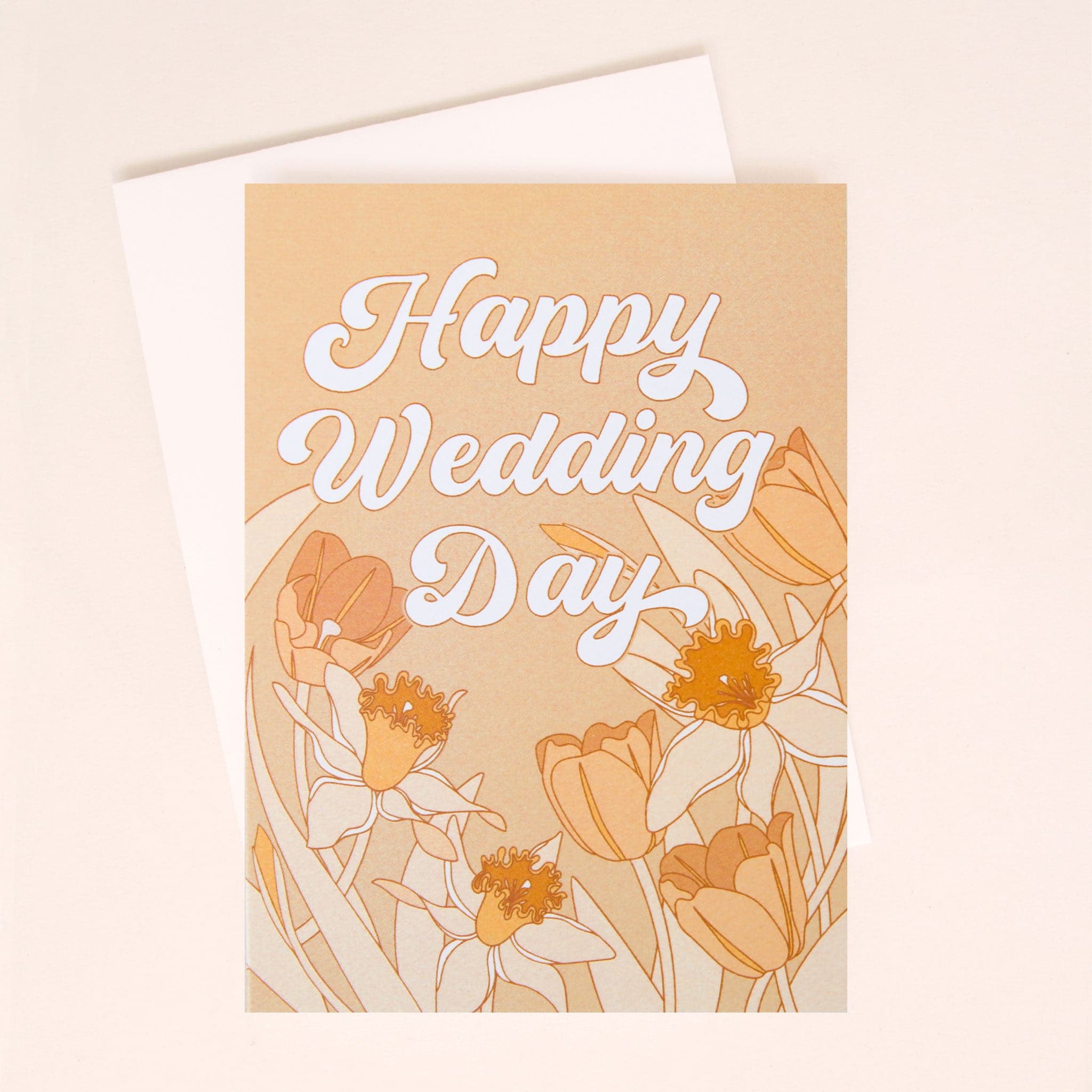 A pink card with white bubble cursive text that reads, &quot;Happy Wedding Day&quot; along with tulip and daffodil illustrations along the bottom. The card also comes with a white envelope.