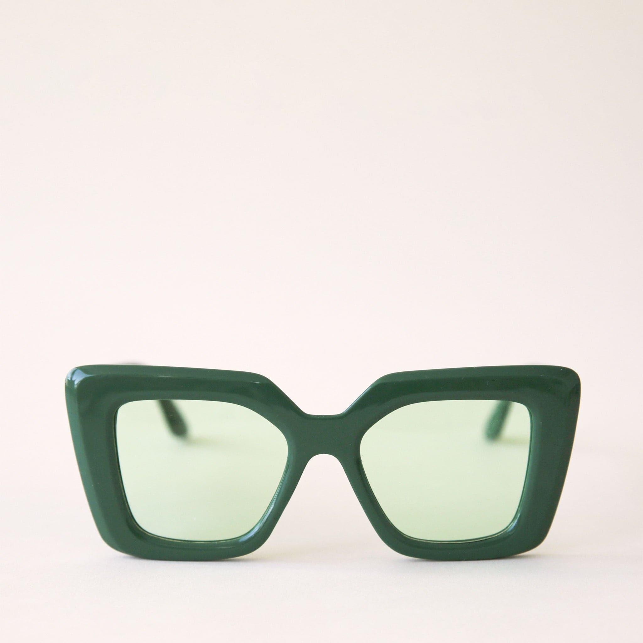 70's inspired sunglasses with a dark green, rectangle frame that has a slight cat eye point at the tops along with light green lenses.